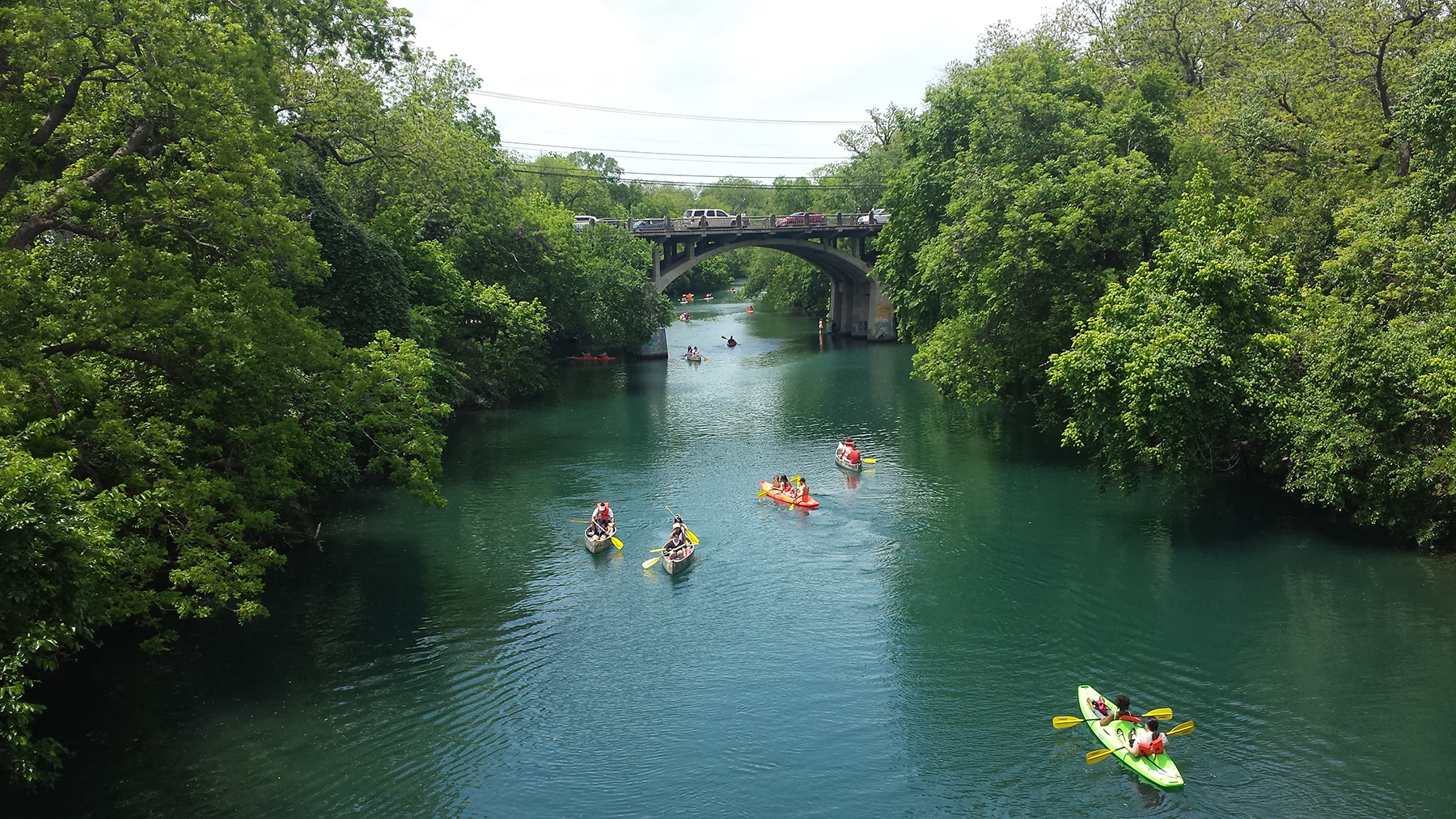 View of bridge, greenery and boats on Lady Bird Lake in Austin