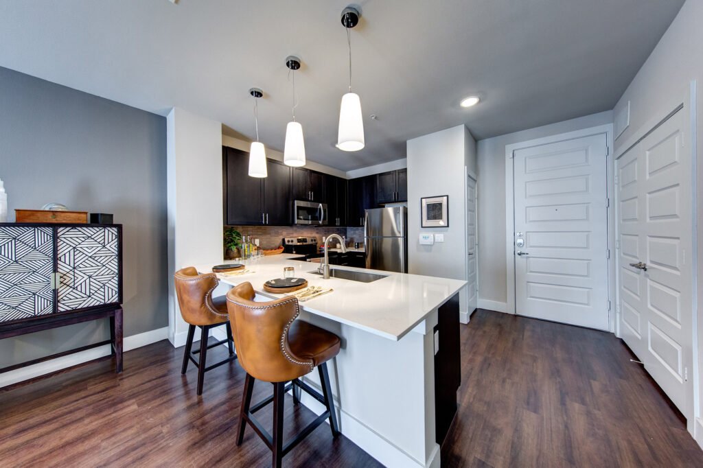 Kitchen with quartz counters and bar style seating, stainless steel appliances, pantry and designer lighting