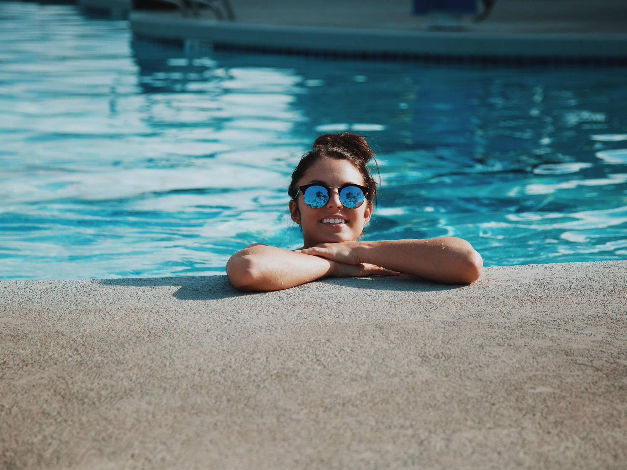 Smiling woman with sunglasses lounges in pool