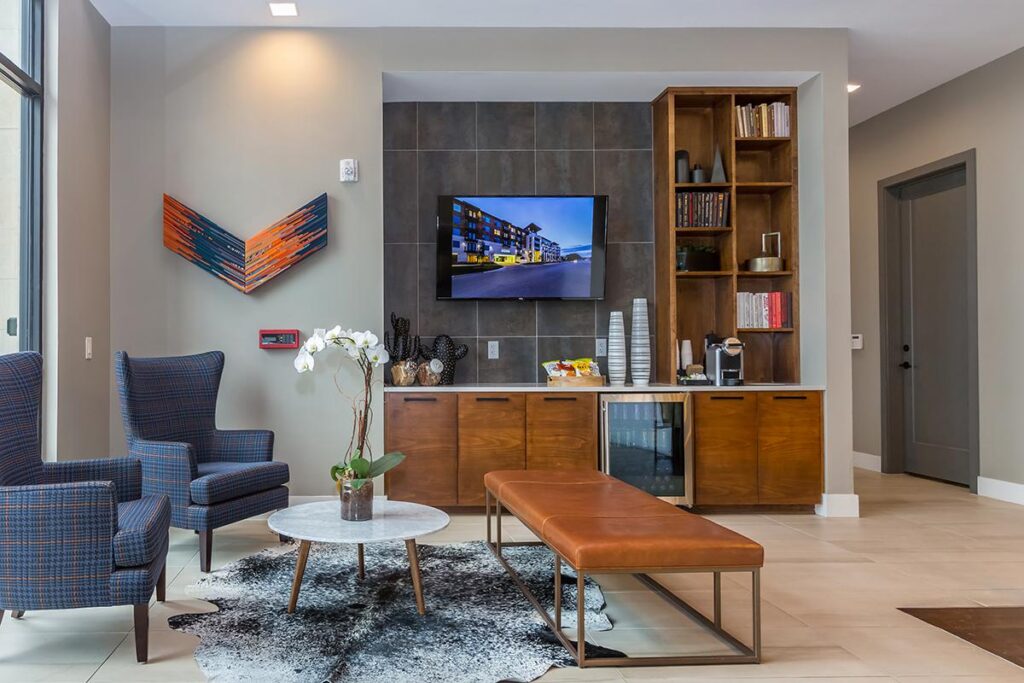 Clubhouse interior kitchen with TV, chairs, bench, and granite flooring