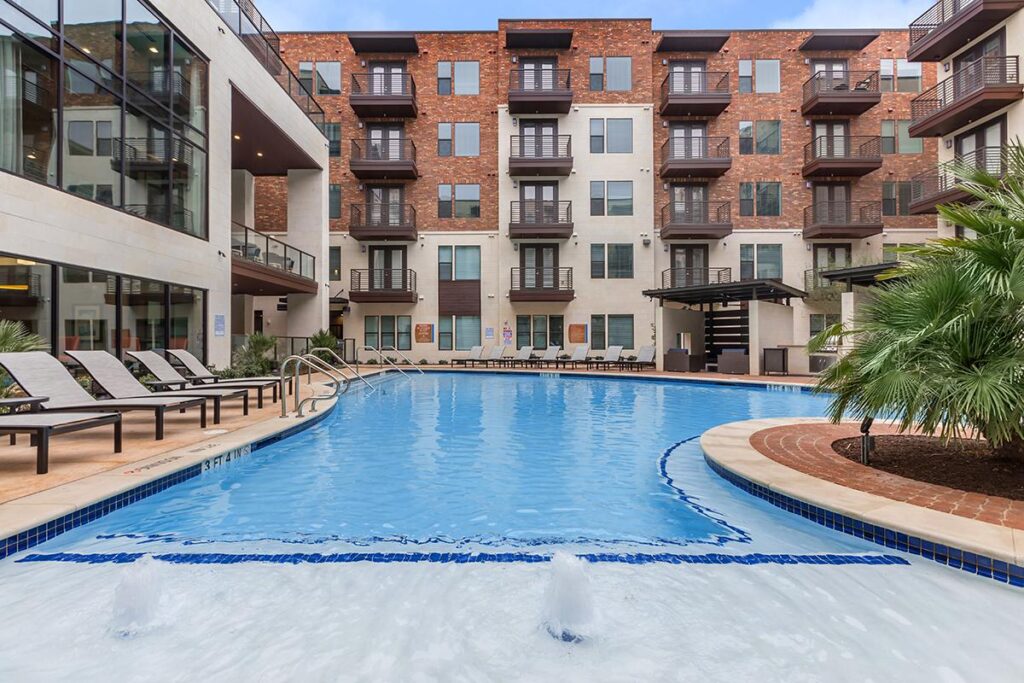 Outdoor pool area with sun tanning beds and tropical landscaping