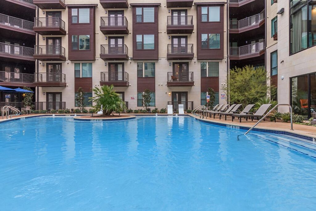 Outdoor pool area with sun tanning beds and tropical landscaping